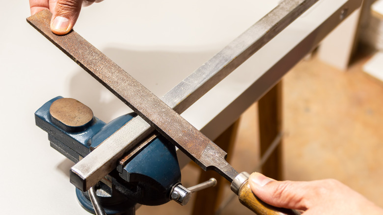 A craftsman using a flat file on a piece of metal