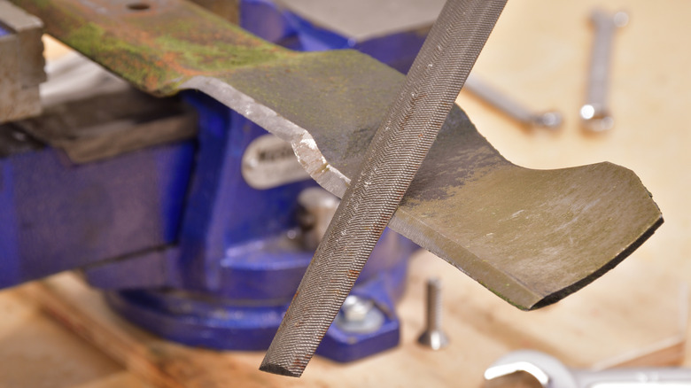 Sharpening a mower blade with a half-round file