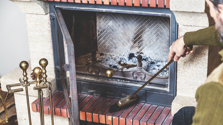 A person brushing dirt off brick fireplace surround
