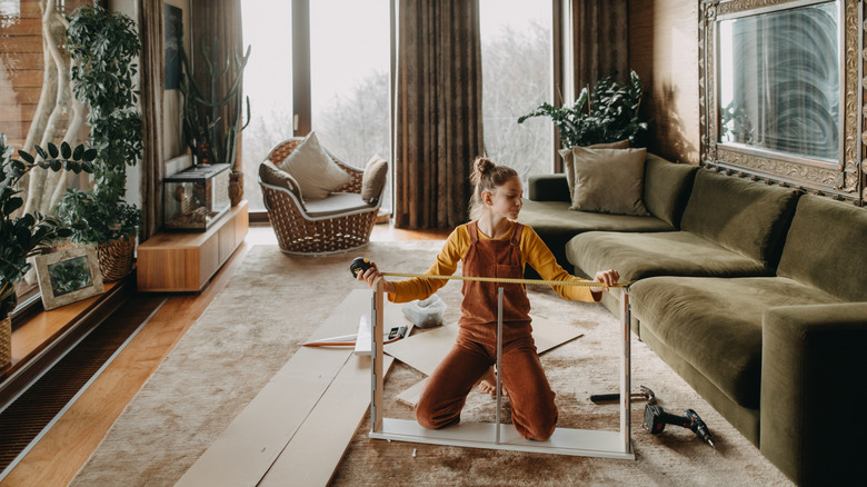 A girl assembling a piece of furniture in a cozily decorated living room
