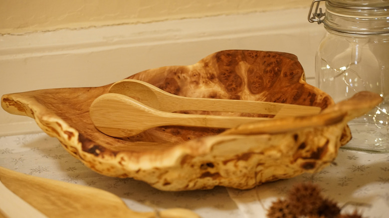 Burl wood serving bowl with wooden tongs on top