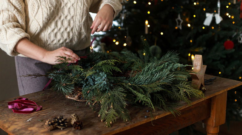 A pair of hands make an evergreen wreath.