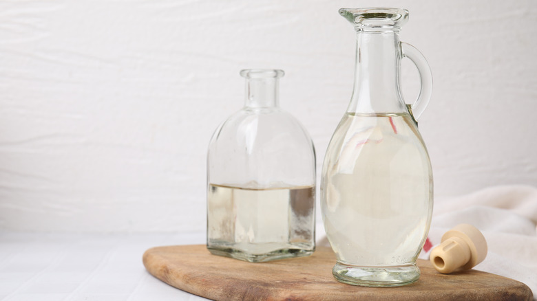 A glass bottle of white vinegar placed on a wooden table