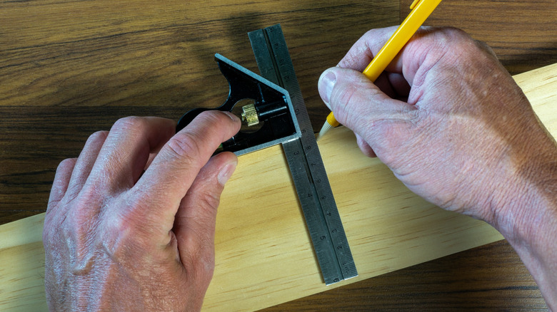 Hands using combination square to draw a line on a piece of wood