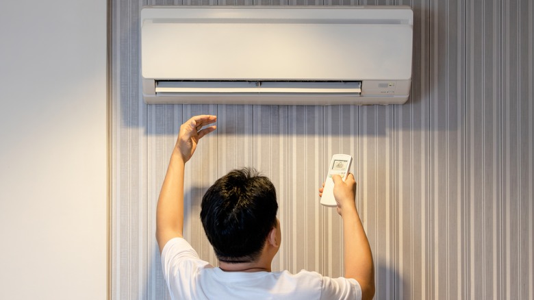 Persona che controlla la temperatura del condizionatore d'aria