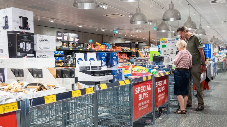 An elderly couple shopping in the aisle of shame in Aldi, looking at some of the Special Buys.