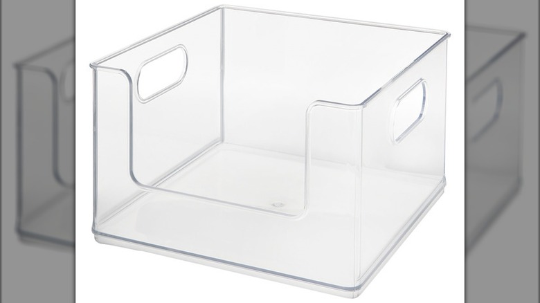 A transparent acrylic organizing bin with handles on each side and a wide opening at the front.