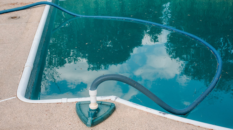A swimming pool with dark water is draining.