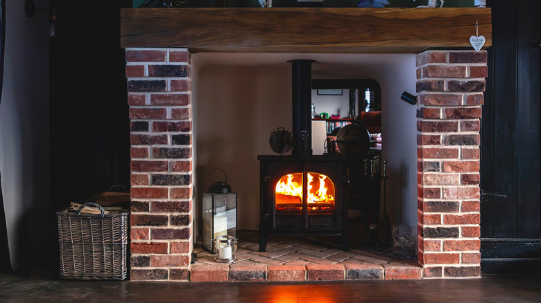 A wood burning stove placed inside a traditional fireplace