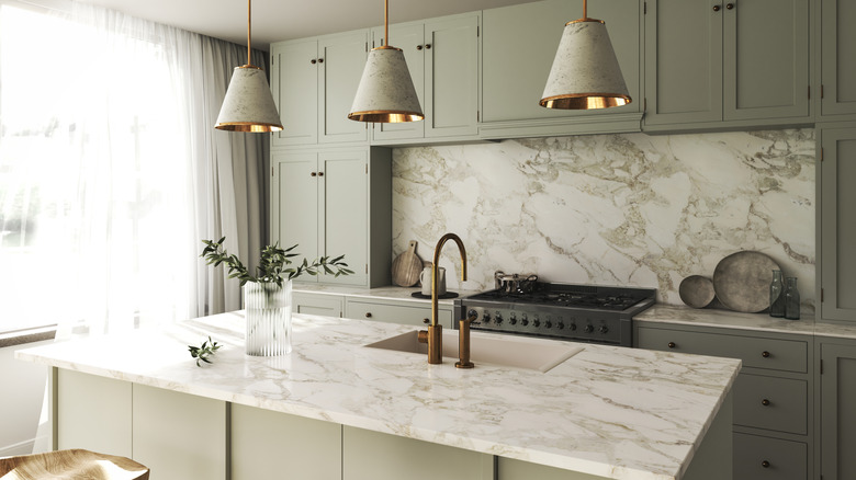 Neutral green kitchen with matching marble backsplash and countertop