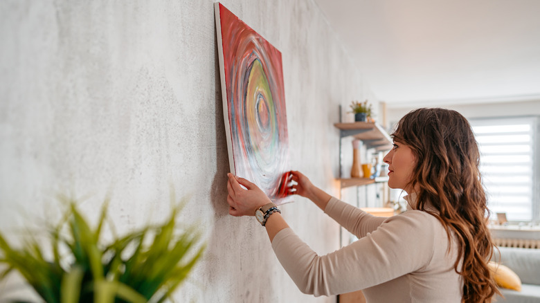 Woman hanging painting on wall