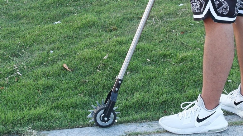 The Baraystus Rotary Edger Tool available at Amazon being used by a man wearing white shoes