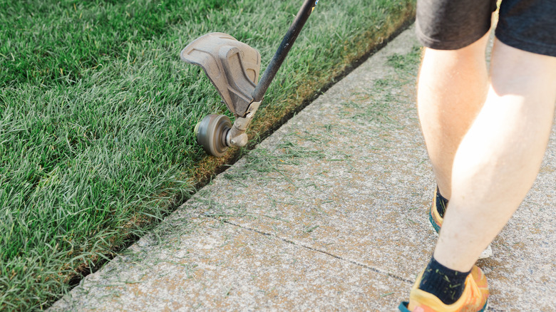 A man using a string trimmer as a lawn edger