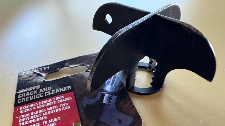 metal spiked weeding tool head next to packaging