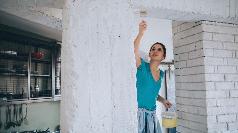A young woman is applying limewash to kitchen walls and masonry