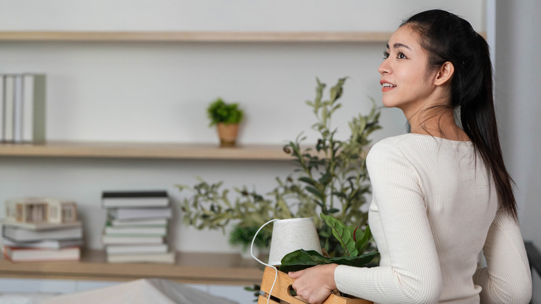 Person organising their home and bringing lights and plants in