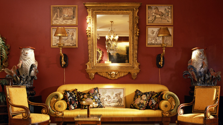 Luxurious gold and red living space with stylish sofa, chairs, and wall art.