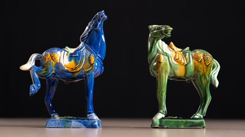 Green and blue horse figurines against black background.