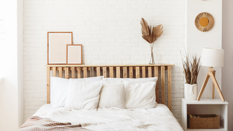 A minimalist bedroom with a white brick wall and wooden headboard.