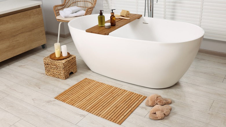 bamboo bath mat in front of a white bathtub