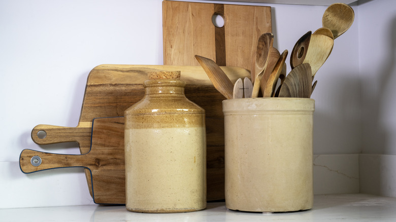 Vintage crock holding wooden utensils on kitchen countertop.