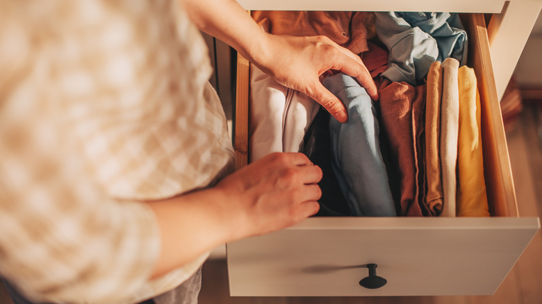 A person reaches for assorted pillow cases in a drawer.