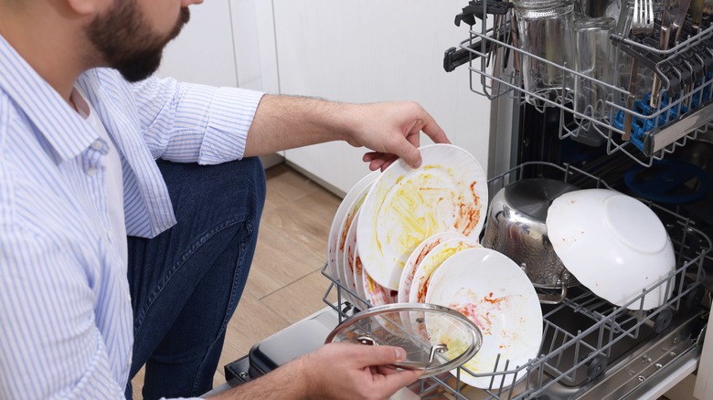 Man loading dirty dishes in dishwasher