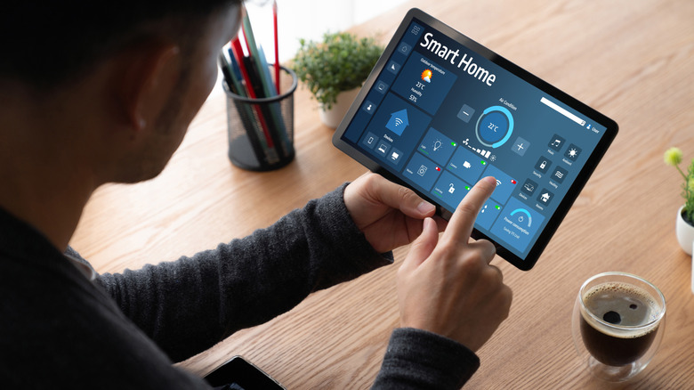 Person using a smart home app on a tablet to control smart devices