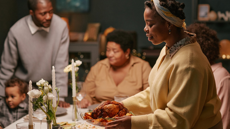 Woman putting a dish on the table while hosting a meal