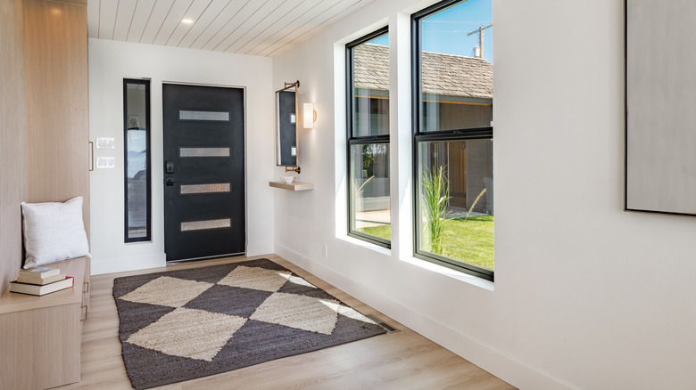 A tidy, spacious entryway with a bench, rug, and closet