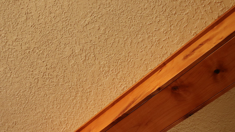 A closeup of a knockdown texture ceiling with a wood beam running through it