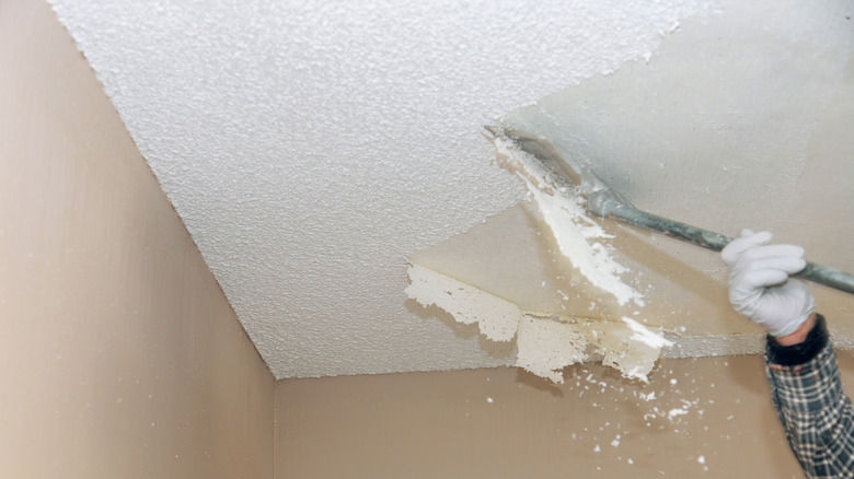 Contractor's hand removing popcorn ceilings