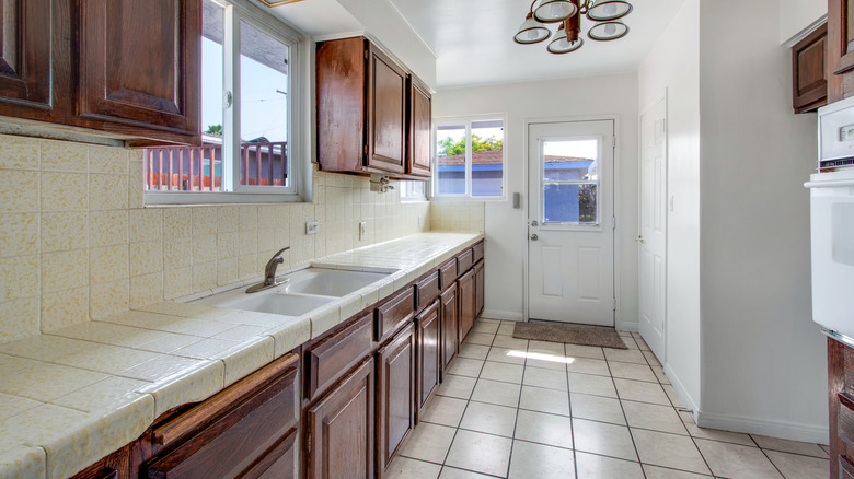 An outdated kitchen with beige tiles and wood cabinets