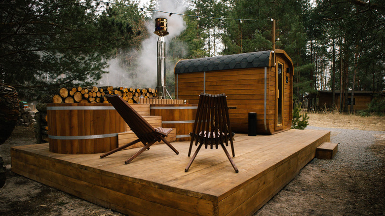A wood-fired sauna and plunge pool with a decking area in a tree-filled backyard.