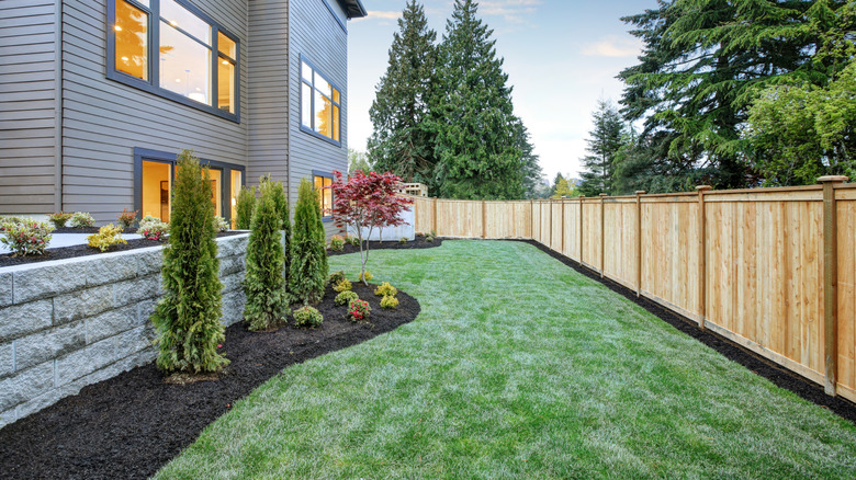 A nicely landscaped backyard with a wooden fence