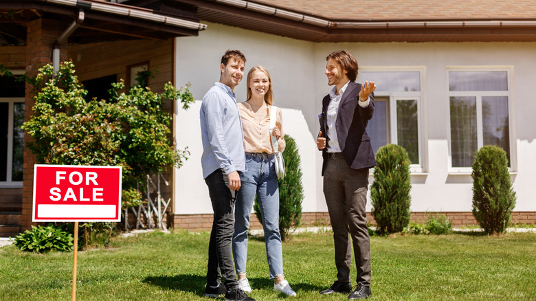 Real estate agent showing couple a backyard of home for sale