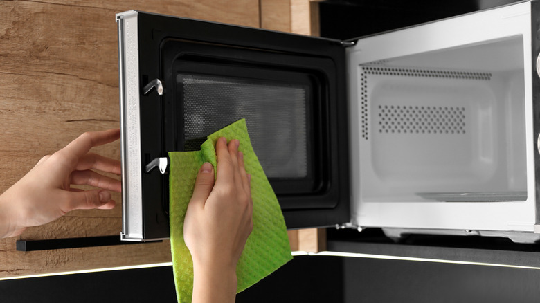 cleaning microwave with green cloth