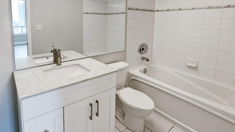 basic white tile bathroom with vanity, toilet, and bathtub