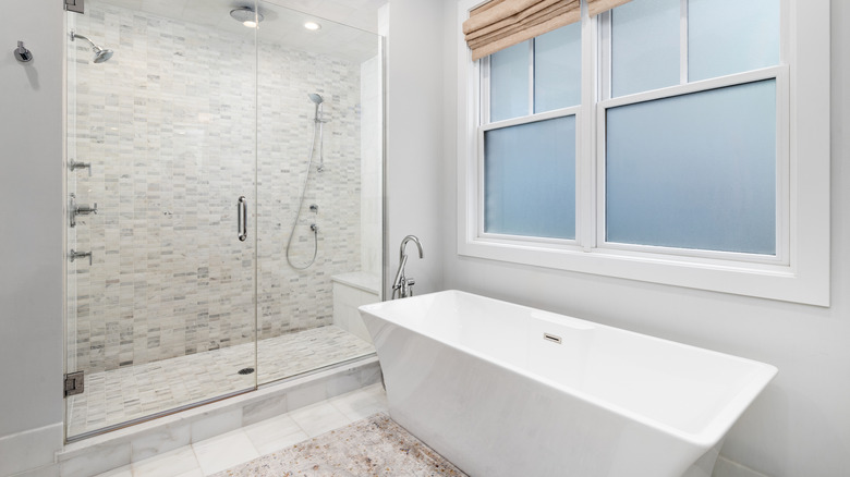 A modern bathroom featuring a freestanding bathtub next to a frosted glass window