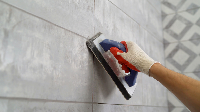Worker making grout repair in bathroom