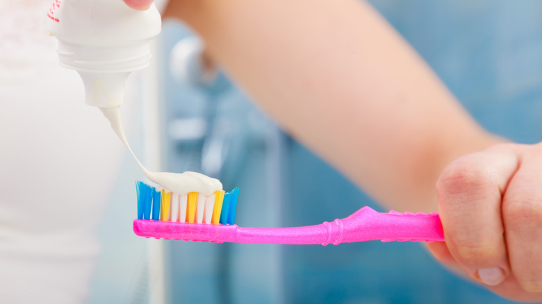 Woman putting toothpaste on brush