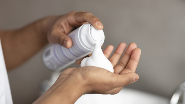 person squirting shaving cream into their hand