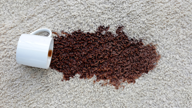 A cup of coffee that has spilled on the carpet
