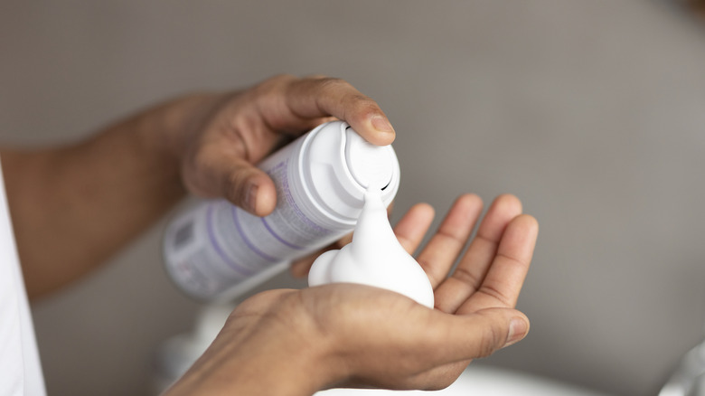 A person putting shaving cream into their hands