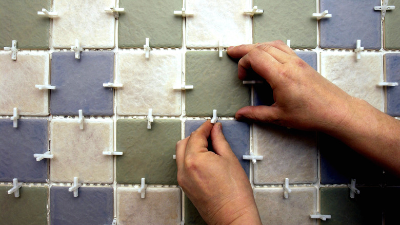 Person installing small tiles in various colors