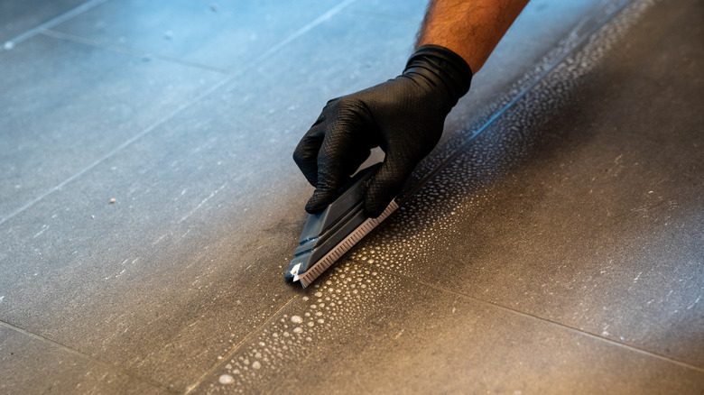 person scrubbing floor grout