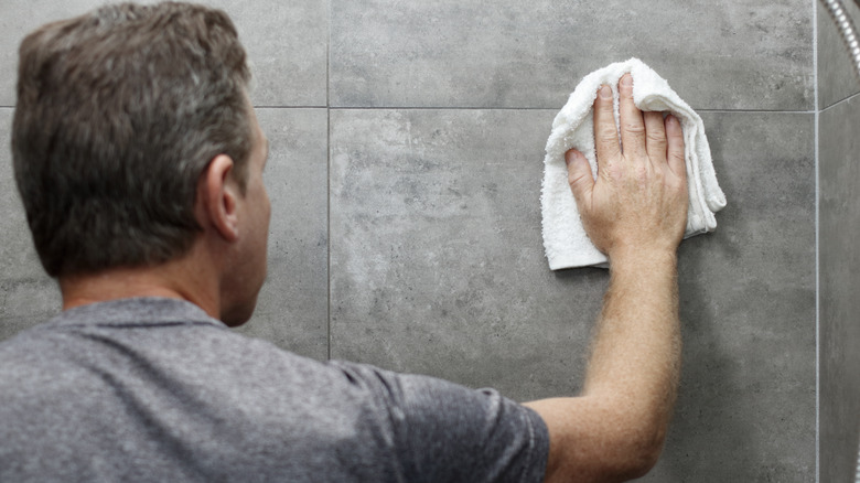 Man wipes down the bathroom tile in the shower