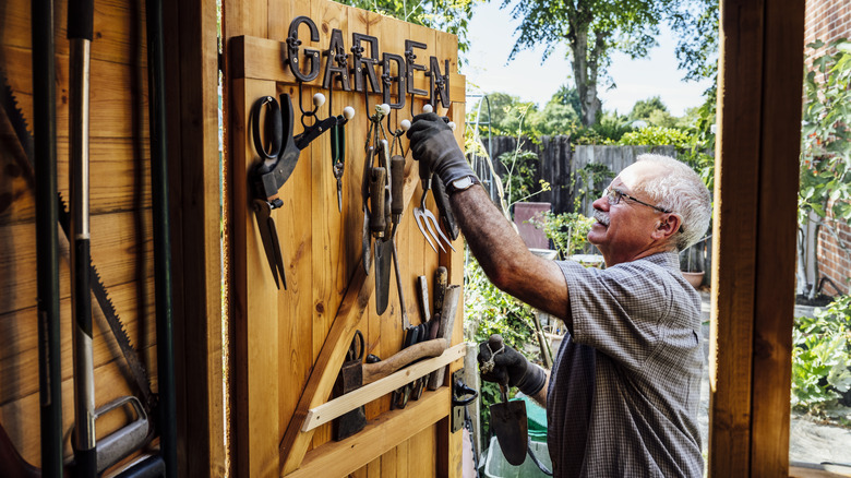 man storing gardening tools