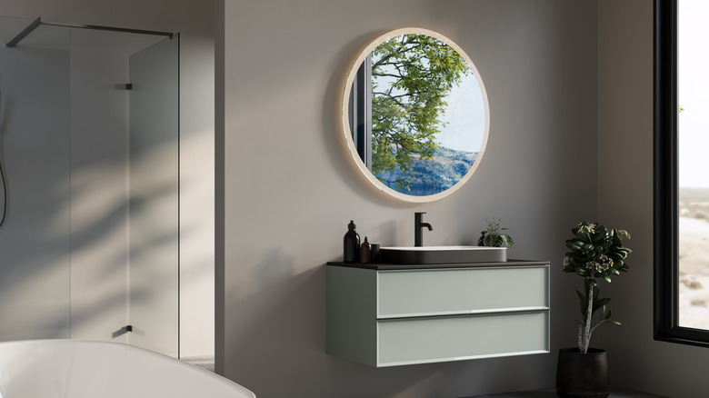 A simple floating shelf with a raised shelf with a round mirror reflecting the outside