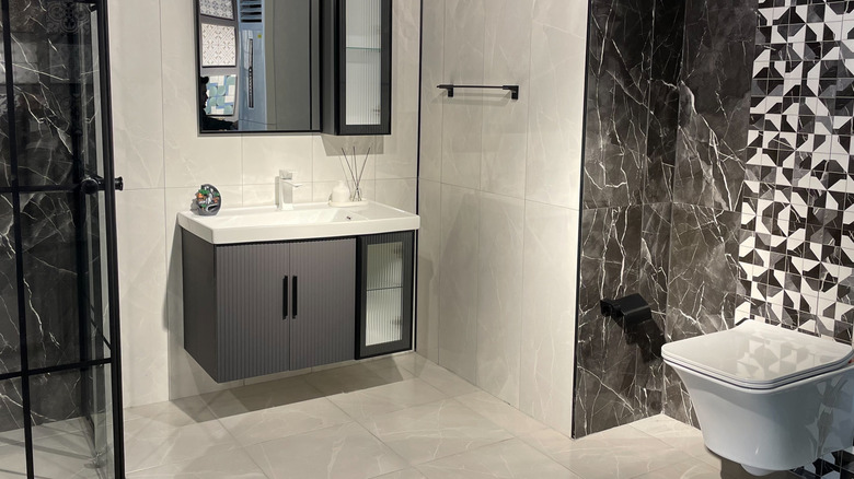 A floatin vanity with closed storage underneath and a medicine cabinet above in a black-and-white bathroom